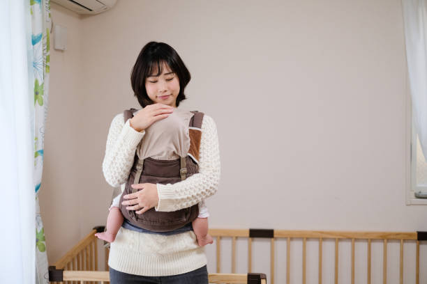 Baby sleeping in arms of mother Everyday life of baby with mother and toddler at home asian nanny stock pictures, royalty-free photos & images