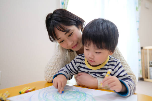 Child drawing picture with mother at home Everyday life of baby with mother and toddler at home joined at hip stock pictures, royalty-free photos & images