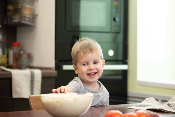 istock Cute kid boy cooking pizza at home kitchen 1071823538