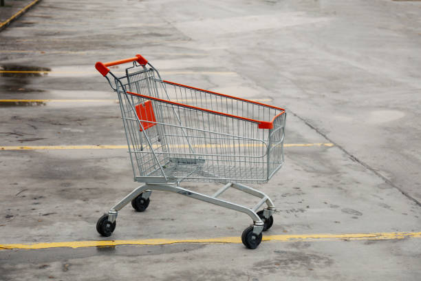 Orange shopping carts parked together in an empty outdoor paved parking lot