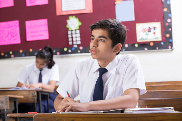 istock male student in classroom writing in notebook - Stock image 1071826226