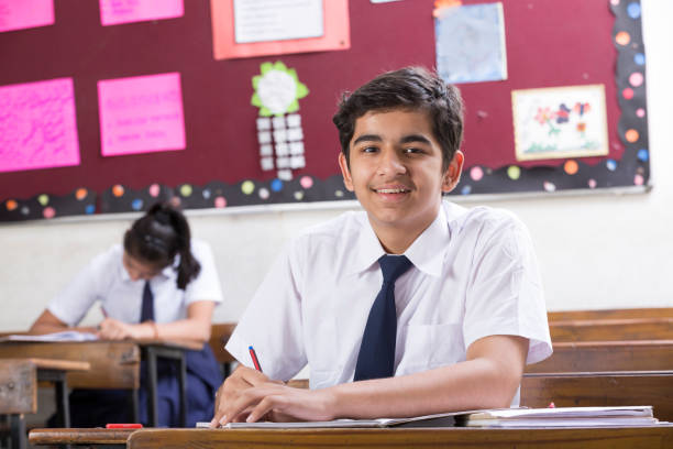 istock male student in classroom writing in notebook - Stock image 1071826944