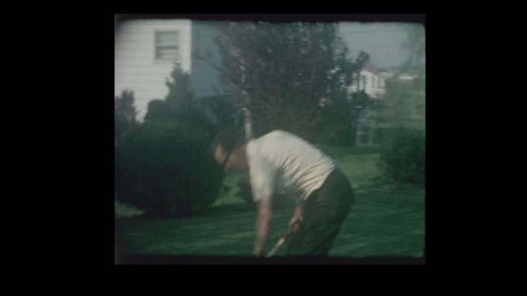 1964 Father and young son playing Badminton in backyard