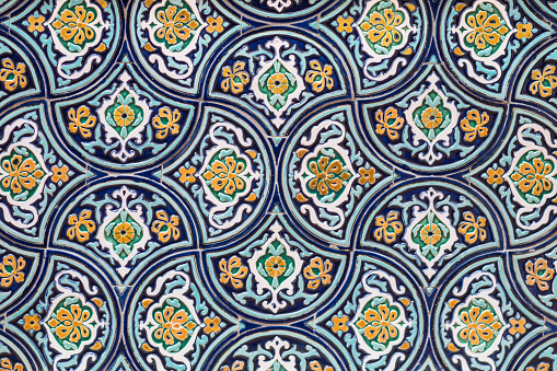 A closeup of oriental ornaments with blue, white and yellow on a wall