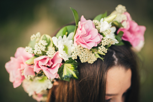 Floral arrangement as a wreath on a head of a brunette woman.