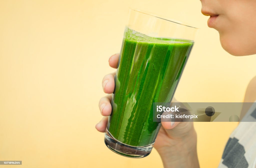 Fresh green smoothie Closeup of female drinking green vegetable smoothie. Green Color Stock Photo