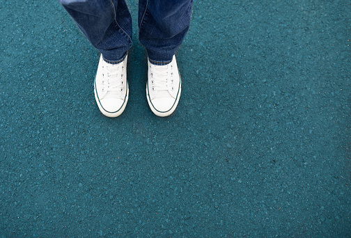 Man in jeans and sneakers walking on city street, closeup. Space for text