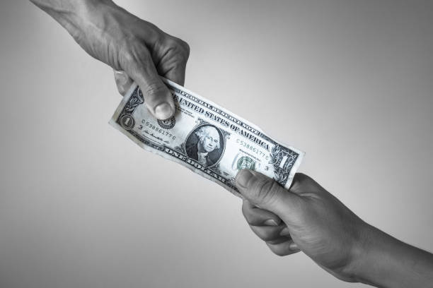 istock Hand giving money one dollar bill to another hand. 1071896814