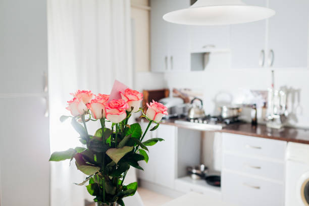 istock Bouquet of roses with card left on kitchen. Modern kitchen design. Interior of kitchen decorated with flowers. 1071898894