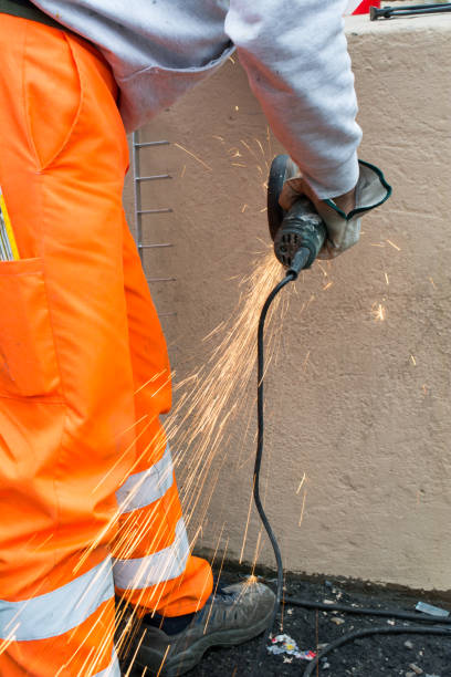 istock Worker using an Orbital Grinder on Steel Surface wearing Orange Work Trousers and Safety Tools 1071913412