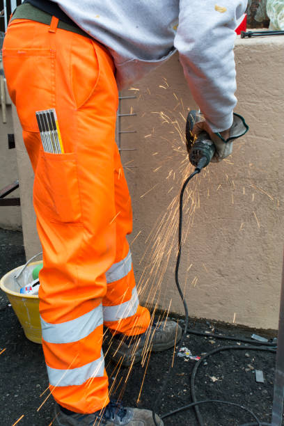 istock Worker using an Orbital Grinder on Steel Surface wearing Orange Work Trousers and Safety Tools 1071913624