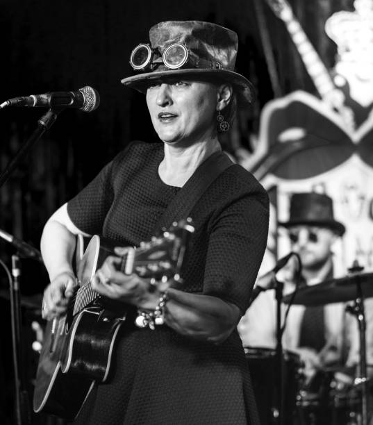 the video portrait of the mature, 45-years-old, woman, musician and singer, wearing the steampunk costume with the hat and googles - band 40s imagens e fotografias de stock