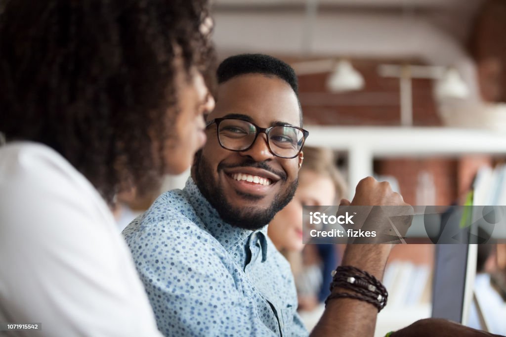 Lächelnde afrikanische amerikanische männliche Mitarbeiter Blick auf Kollegen chatten - Lizenzfrei Büro Stock-Foto