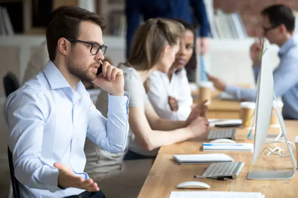 Photo of Angry male worker talk on phone solving business problems