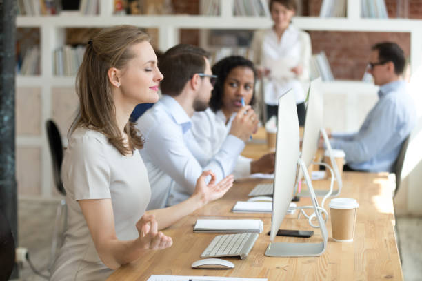istock Peaceful female employee meditating at workplace in shared office 1071915616