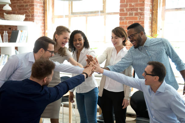 muy contentos los trabajadores diversas unir sus manos en la actividad de teambuilding - espectáculos fotografías e imágenes de stock