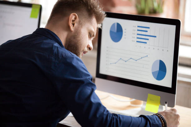 istock Male employee working with graphs on pc in office 1071915662
