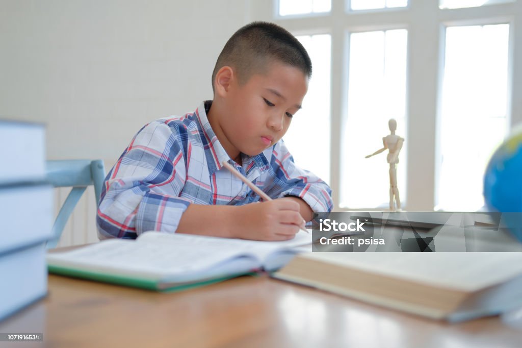 kleine asiatische Kind junge Schüler schreiben auf Notebook. Kind Kinder Hausaufgaben. - Lizenzfrei Asien Stock-Foto