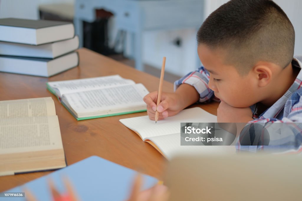 kleine asiatische Kind junge Schüler schreiben auf Notebook. Kind Kinder Hausaufgaben. - Lizenzfrei 8-9 Jahre Stock-Foto