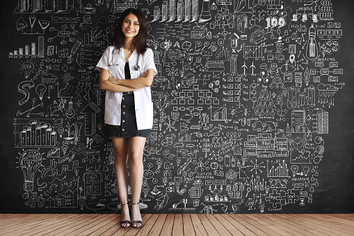 Young adult doctor drawing plans on blackboard.