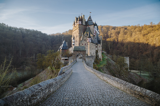 Beautiful view of famous Eltz Castle in scenic golden morning light at sunrise with blue sky on a sunny day in fall with retro vintage VSCO style filter effect, Wierschem, Rheinland-Pfalz, Germany