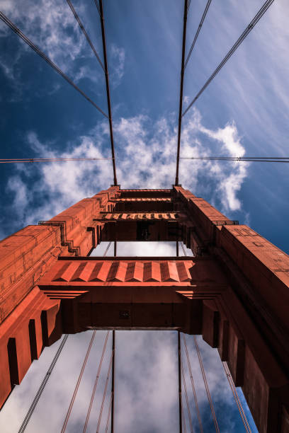 タワーのゴールデン ゲート ブリッジ、雲と橋の上の青い空と明るい晴れた日に下から見上げて - golden gate bridge bridge large san francisco county ストックフォトと画像