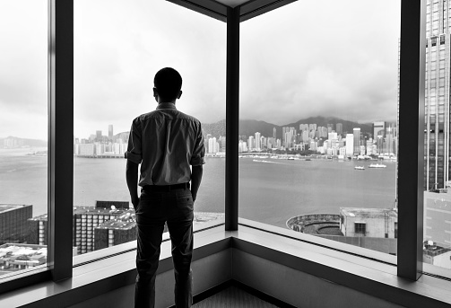 Businessman looking at city through office window