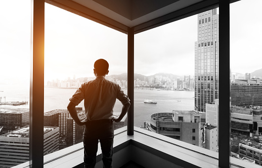 Businessman looking at city through office window