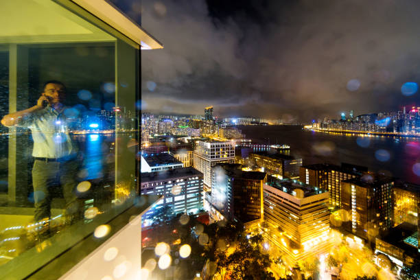 Businessman standing by the window and using phone at night.