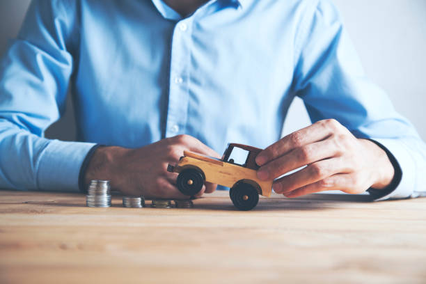 istock Businessman a toy car and a stack of coins 1071985994