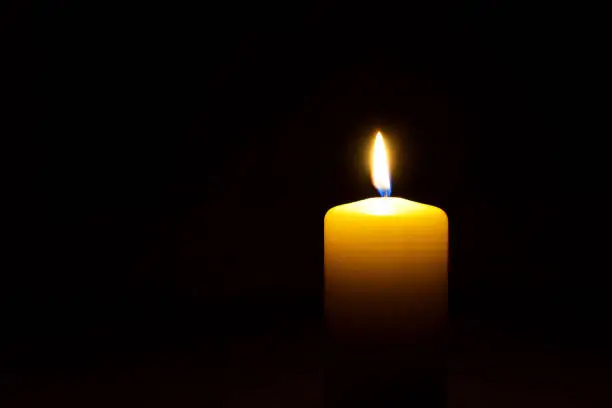 Photo of One yellow candle flame  burning in darkness