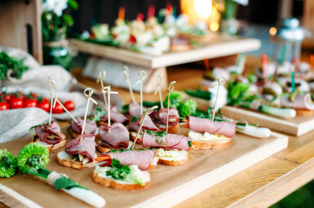 istock Delisious catering banquet buffet table decorated in rustic style in the garden. Different snacks, sandwiches with ham and pesto sauce. Outdoor, closeup. 1072005180