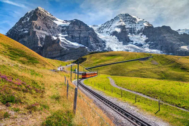 Famous electric red tourist train coming down from the Jungfraujoch station(top of Europe) in Kleine Scheidegg. Eiger North face in background, Grindelwald, Bernese Oberland, Switzerland, Europe
