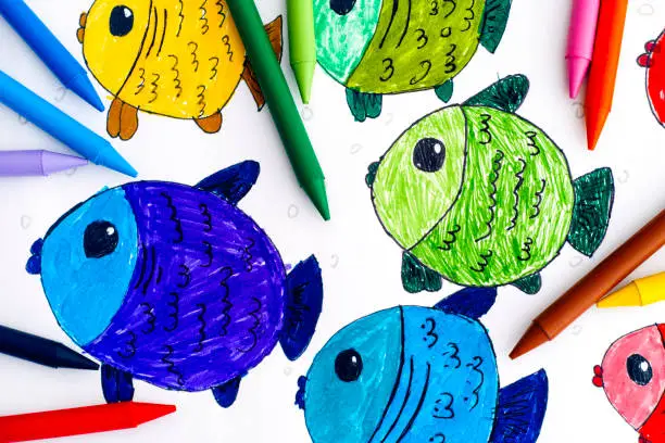 Photo of Multicolored fishes. Child hand drawing with colored crayons.