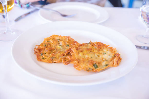 two little shrimp omelette fried with parsley, typical Andalusian food and Spanish tapas, in dish on white tablecloth of restaurant in Spain