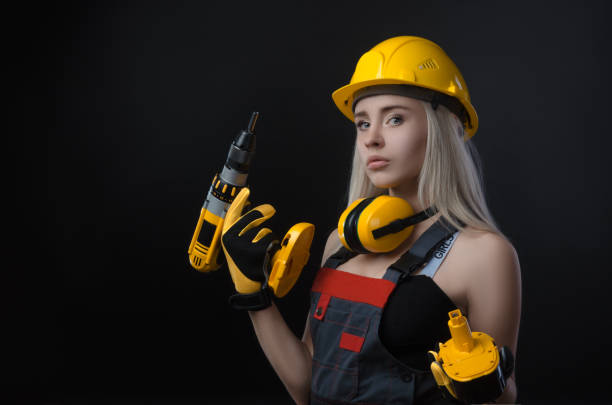 istock girl in construction clothes and protective equipment posing with a screwdriver 1072032442
