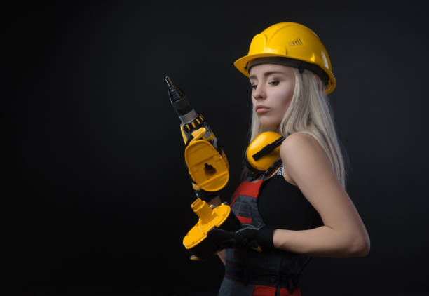 istock girl in construction clothes and protective equipment posing with a screwdriver 1072032444