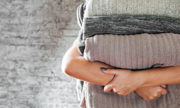 istock woman holding in hands Stack of cozy knitted sweaters on gray wall background 1072035674