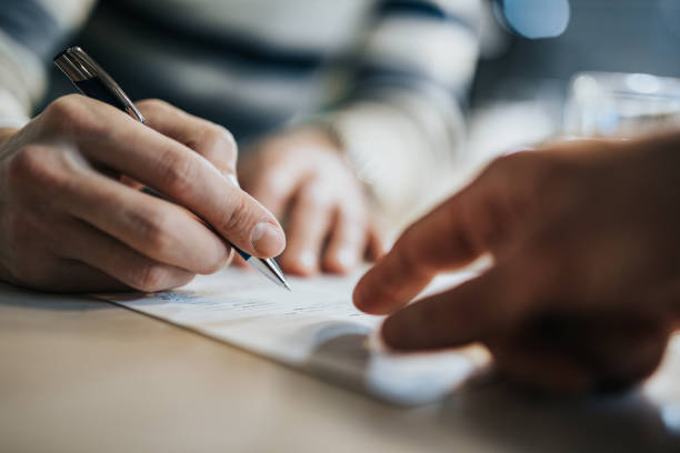 Sign here please! Close up of unrecognizable man signing a contract while financial advisor is aiming at the place he need to sign. financial loan stock pictures, royalty-free photos & images