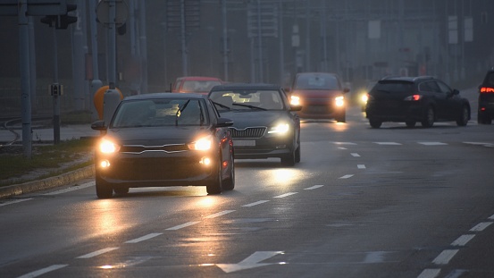 Coches en la niebla. El clima de invierno mal y peligroso tráfico de automóvil en el camino. Vehículos ligeros en día brumoso. photo