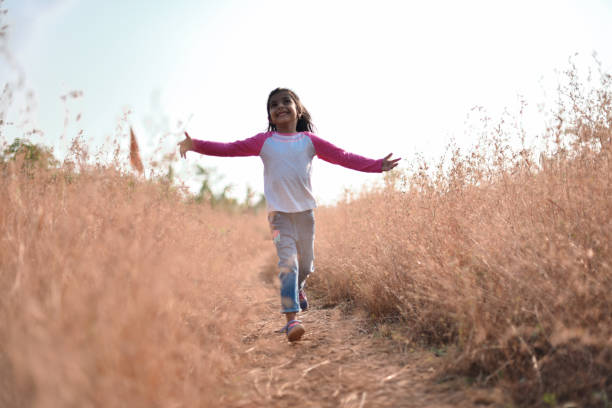 istock Young girl running through dry grass 1072051866