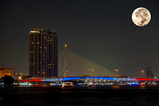 The beauty of the full Moon at Chao Phraya River and Pinklao Bridge , Bangkok Thailand.