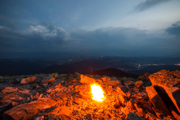 istock Beautiful summer night in mountain. Bright fire burns on rocky mountain top under blue cloudy sky. 1072060774