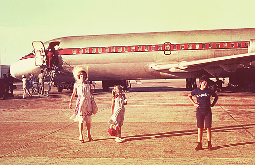 Vintage image of a mother and her children before boarding an airplane on a summer vacation.
