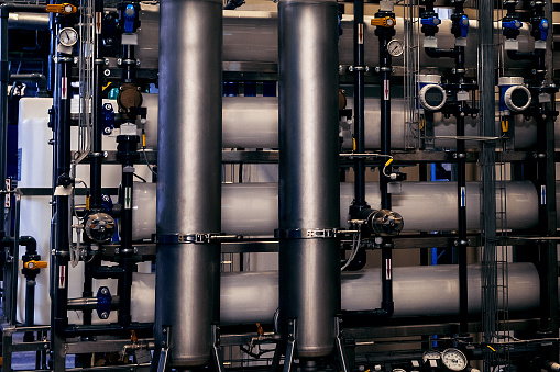Side view of the industrial pipelines with filters and heat exchangers in the industrial boiler plant room.