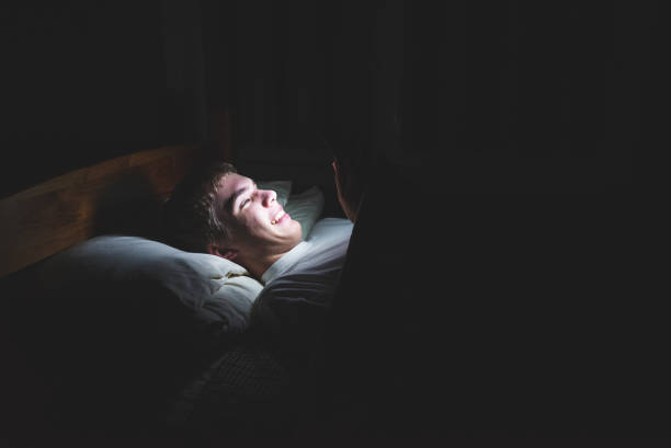 Excited teenager watching a video in the dark. stock photo