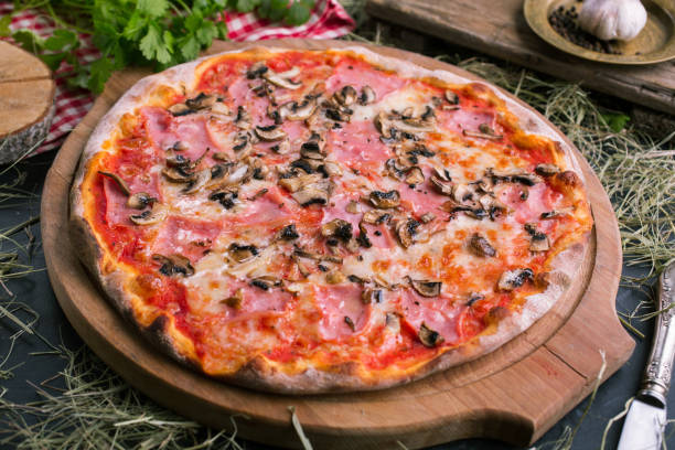 istock Pizza with ham and mushrooms on wooden background 1072076400
