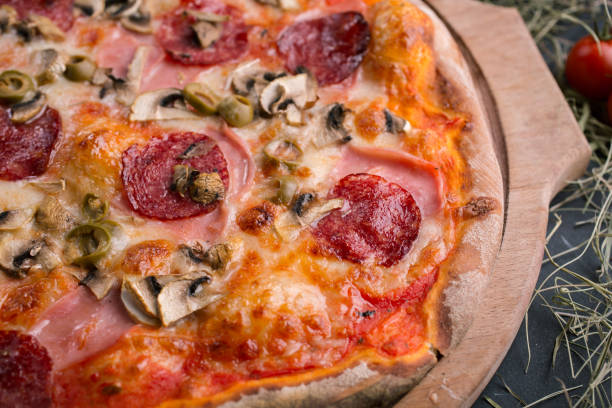 istock Pizza with ham and mushrooms on wooden background 1072076890