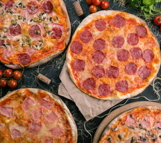 istock Pizzas salami on wooden background with fresh tomatoes 1072076906
