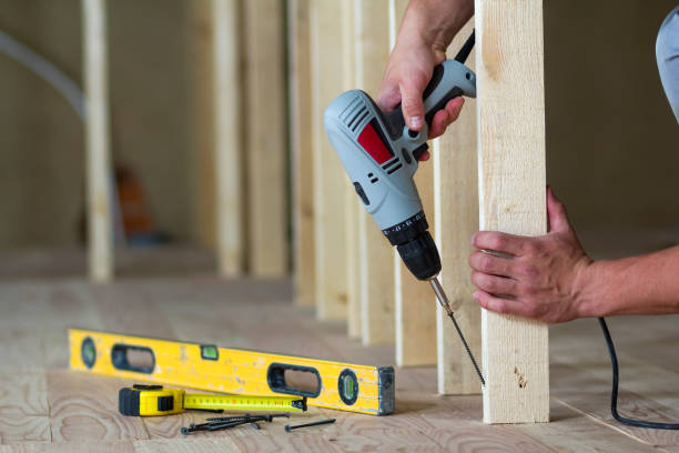 Close-up of worker's hands with screwdriver on background of professional tools and wooden frame for future wall in unfinished attic room under reconstruction. Renovation and improvement concept. primer plano de manos de los trabajadores con un destornillador sobre fondo de herramientas profesionales y marco de madera de la futura pared de habitación de la buhardilla sin terminar en reconstrucción. concepto de renovación y mejora.